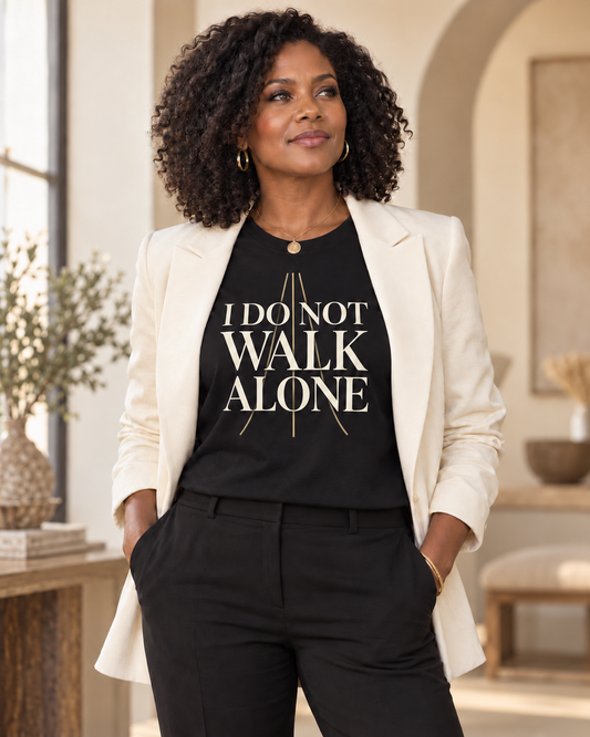 Woman wearing the I Do Not Walk Alone black relaxed T-shirt with an ivory blazer.